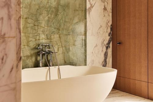 a white tub in a bathroom with a marble wall at The Berkeley, Maybourne in London