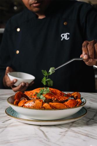 a person holding a spoon and a plate of food at Radisson Collection Resort Galle in Galle