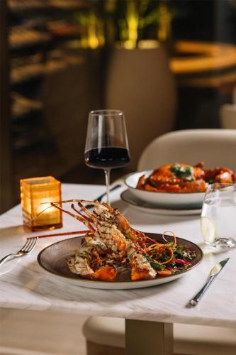 a table with two plates of food and a glass of wine at Radisson Collection Resort Galle in Galle
