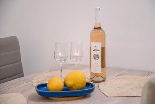 a table with two glasses and two lemons and a bottle of wine at Maggano Paros Apartments 3 in Angairiá