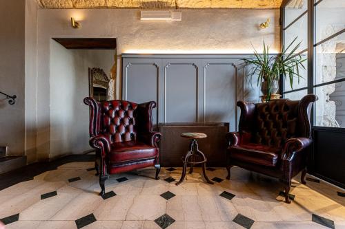 two leather chairs and a table in a room at Saint Amand by Palazzo Boyl in Cagliari
