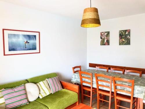 Una sala de estar con un sofá verde y una mesa. en Appt T4 Résidence Le Cordouan 3 étoiles côté Piscine, en Soulac-sur-Mer