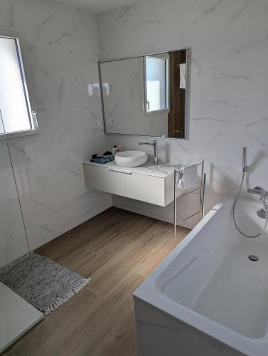 une salle de bain blanche avec un lavabo et un miroir dans l'établissement Magnifique maison proche des plages, à Plouzané