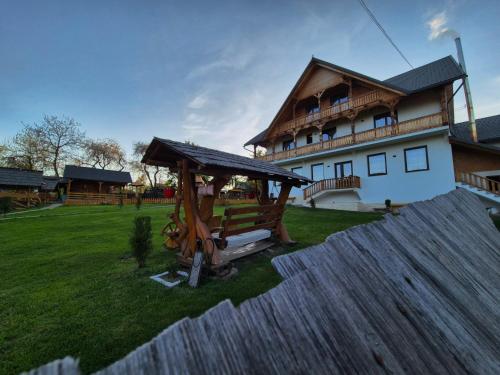 a house with a gazebo in front of a yard at Pensiunea Maramu in Breb