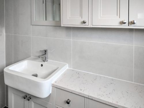 a bathroom with a white sink and white cabinets at Sea Glimpse in West Runton