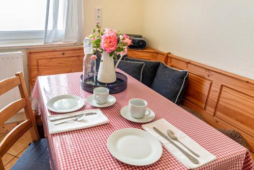 a table with plates and cups and a vase with flowers at Joos Boardinghouse in Radolfzell am Bodensee