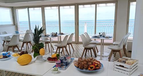 a table with food on it with chairs and windows at Hotel Club Perla in Casalabate