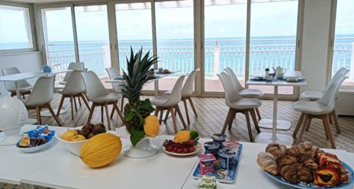 a table with food on it with chairs and windows at Hotel Club Perla in Casalabate