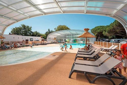- une piscine avec un groupe de chaises longues et un bâtiment dans l'établissement Camping 4 étoiles - Parc aquatique - eeibgd, à Royan