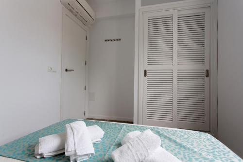 a white bedroom with a bed with towels on it at Apartamentos Pou Des Pujols in Es Pujols