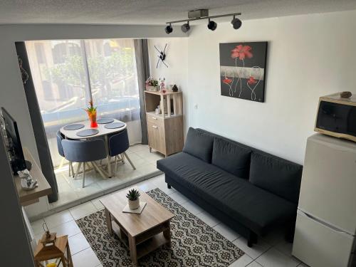 un salon avec un canapé bleu et une table dans l'établissement appartement 2 étoile à moins de 100m de la plage vu sur Le Canigó, à Saint Cyprien Plage