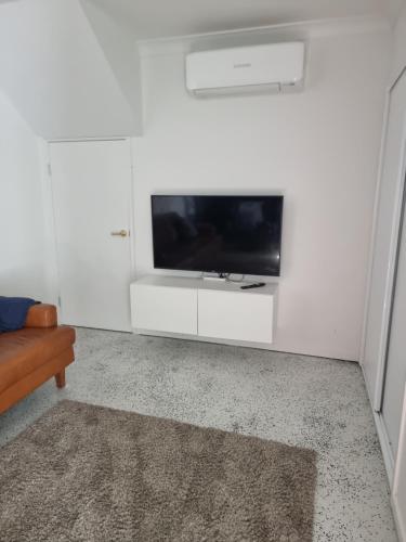a living room with a tv on a white wall at Retreat with horse stable views in Redcliffe