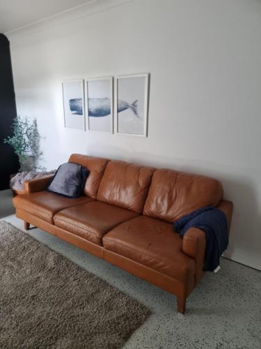 a brown leather couch sitting in a living room at Retreat with horse stable views in Redcliffe