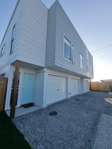 a white house with two garages and two garage doors at Retreat with horse stable views in Redcliffe