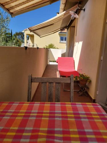 - deux chaises rouges assises sur la terrasse couverte d'une maison dans l'établissement Appartement de 30m2 agréable et chaleureux, à Pérols