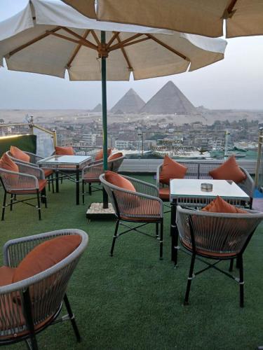 a group of chairs and tables with an umbrella at ALADDIN PYRAMIDS View in Cairo