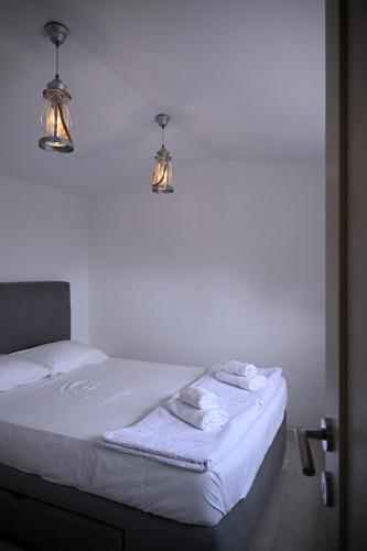 a white bed with two lights and towels on it at Apartments Danica in Petrovac na Moru