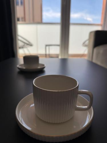 a white coffee cup on a plate on a table at Royal Apartments in Skopje