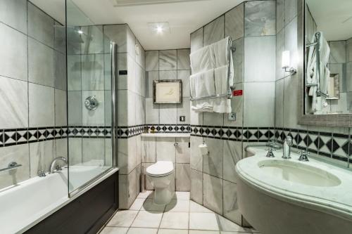 a bathroom with a tub and a toilet and a sink at Wood Hall Hotel & Spa in Wetherby
