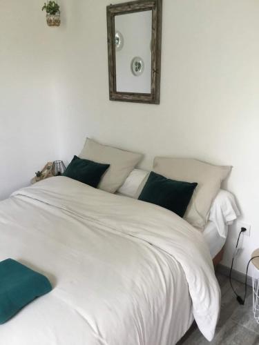 - un lit blanc avec des oreillers verts et un miroir dans l'établissement Studio à 50M de la mer avec SPA, à Grandcamp-Maisy