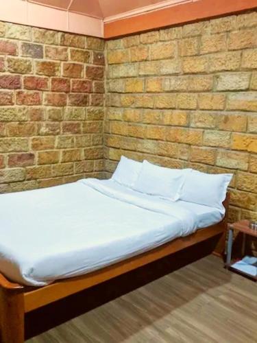 a bed in a room with a brick wall at Smoky Falls Mae Fi Resort in Cherrapunji