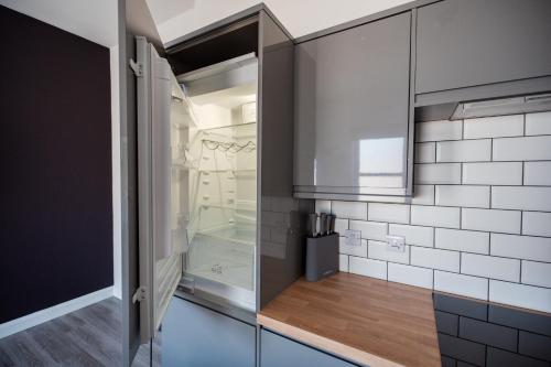 een keuken met een glazen koelkast en witte tegels bij The Bishops Nest in Bishop Auckland