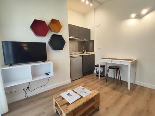 a living room with a table and a tv and a kitchen at Hotel Rural Tierras del Cid in Quintanadueñas