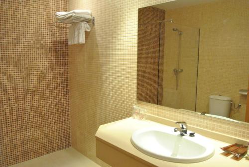 a bathroom with a sink and a mirror and a toilet at Motel Cancun Oviedo in Llanera
