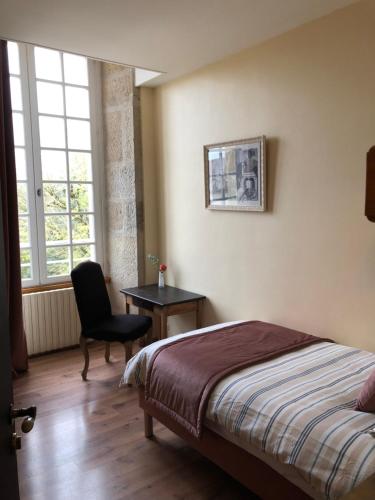 a bedroom with a bed and a chair and a window at Domaine familial du château de Ragny in Savigny-en-Terre-Plaine