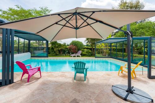 a patio with chairs and an umbrella next to a pool at Villa d exception 3 étoiles in Clermont