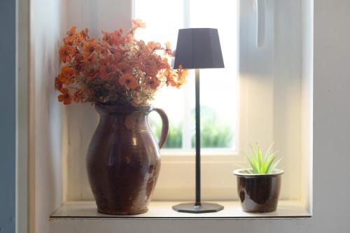 a vase with flowers on a window sill next to a lamp at Vogelsberger Bett unser Korkhaus in Köddingen