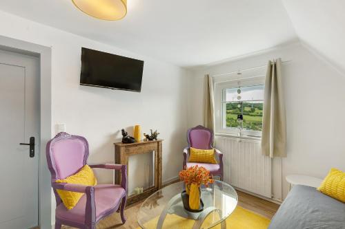 a living room with purple chairs and a glass table at Vogelsberger Bett unser Korkhaus in Köddingen
