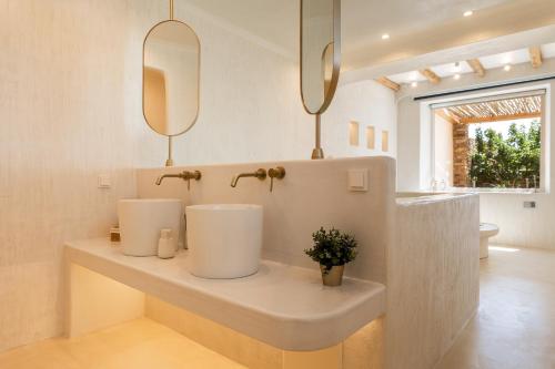 a bathroom with a sink and two mirrors at Youtopia Ios Villas in Ios Chora