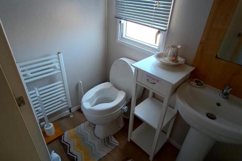 Un baño blanco con inodoro y lavabo. en Comfortable family caravan in Weymouth, en Weymouth