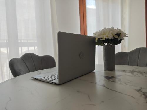 a laptop computer sitting on a table with a vase of flowers at Dimora Alessandrina in Alessandria