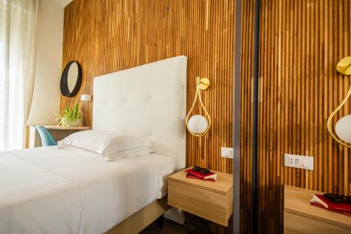 a bedroom with a white bed and a wooden wall at Hotel Terme Formentin in Abano Terme
