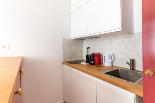 une cuisine avec des armoires blanches et un évier dans l'établissement Nicolo Passy Magnifique Studio, à Paris
