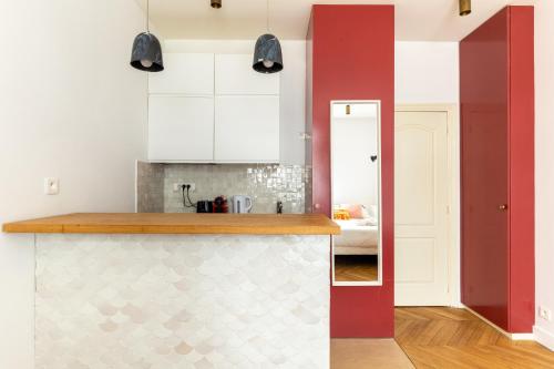 une cuisine avec des placards blancs et un mur rouge dans l'établissement Nicolo Passy Magnifique Studio, à Paris