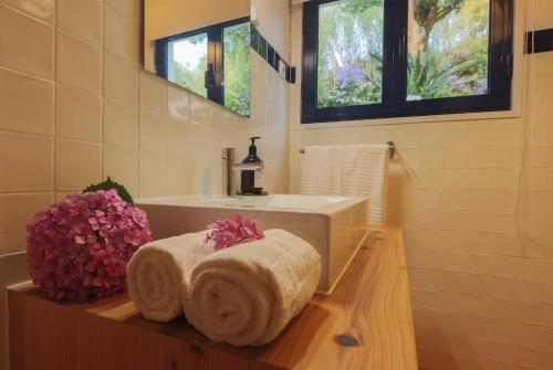 a bathroom with a sink and a tub with towels at Green OceanView Relaxing Cottage in Mosteiros