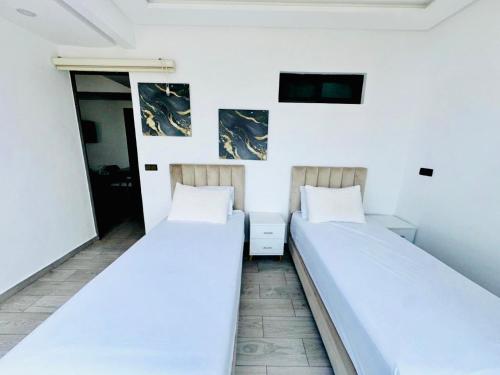 two beds in a room with white walls at 2 minutes de la plage , Résidence Tamourrit, Taghazout Bay , vue mer , golf , piscine in Taghazout