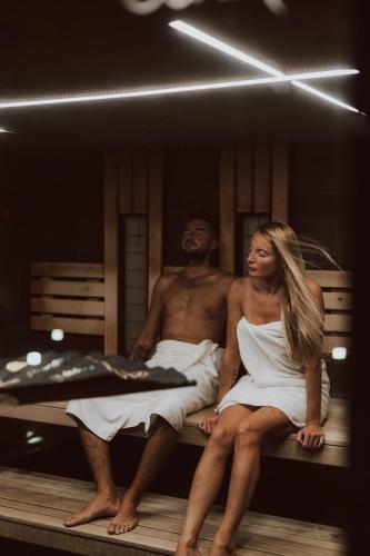 a man and a woman sitting on a bench at Lake Hill Karkonosze Resort & Spa in Sosnówka