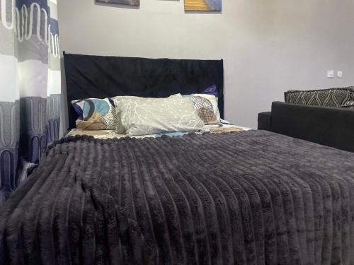 a bed with a black comforter and pillows on it at Skl apartment in Adentan