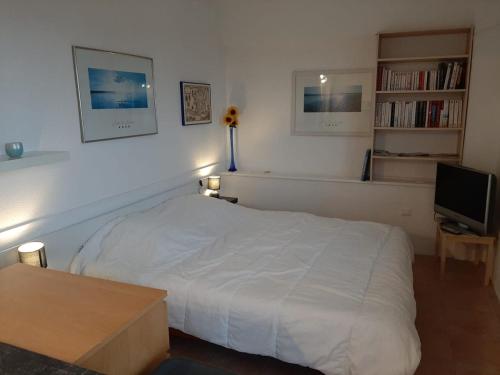 une chambre avec un lit blanc et une télévision dans l'établissement Belle maison Lila Jade avec superbe vue à 180 degrés piscine partagée, à Laroque-des-Albères