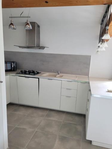 une cuisine blanche avec un évier et une cuisinière dans l'établissement Petite maison avec jardin à 10min des plages, à Villeneuve-lès-Maguelone