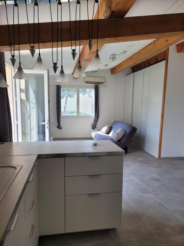 une cuisine avec des armoires blanches et un canapé dans une pièce dans l'établissement Petite maison avec jardin à 10min des plages, à Villeneuve-lès-Maguelone