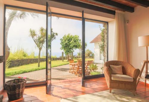 un soggiorno con porte scorrevoli in vetro che si aprono su un patio. di Blue OceanView Relaxing Cottage a Mosteiros