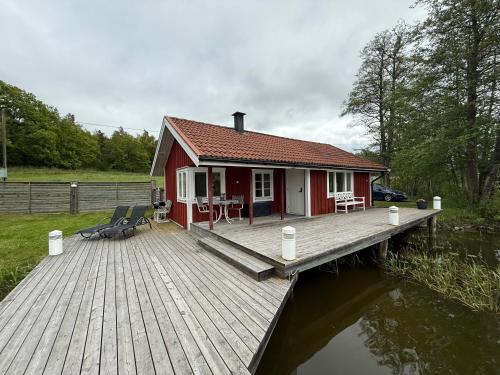 a red house on a dock next to the water at Sjöstugan in Söderköping