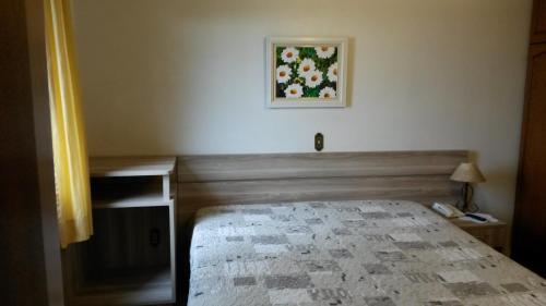 a bedroom with a bed and a picture on the wall at Hotel San Carlos in Carlos Barbosa