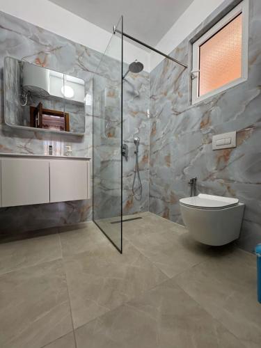 a bathroom with a shower and a toilet and a sink at Viron Apartament in Himare