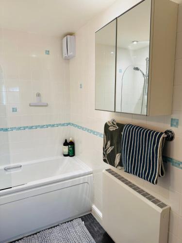 a white bathroom with a tub and a mirror at Fly Hi-Town Centre Apartment in Ifield